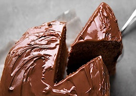 A piece of chocolate cake being removed from the whole